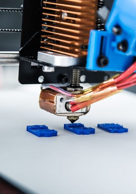 3d,Printer,Mechanism,Working,Yelement,Design,Of,The,Device,During Close up of a 3D printer hotend printing 3 blue parts on the bed of the printer.