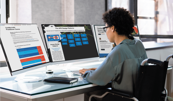 apx dpad a young woman sitting at a desk facing three computer screens. On the computer screens are the AbleGamers apx course information. Support the DPAD Initiative, host a fundraiser
