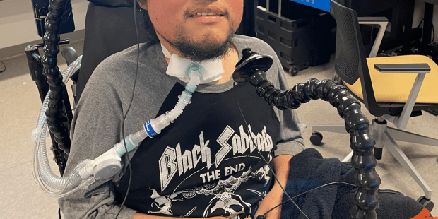 A photo of Carlos getting back to gaming. He has dark hair and a beard he is wearing a Black Sabbath t-shirt