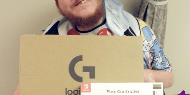 Dillon S. Man with red hair and glasses, in a power wheelchair looking at the camera. He has a Logitech Switch kit and Hori Flex on his lap.