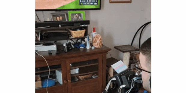 a photo taken from behind Dylan who is playing a baseball video game using a quadstick