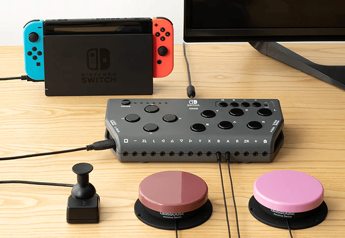 A Hori Flex plugged into a Nintendo Switch. A small joystick, red button, and pink button are all connected and placed in front.
