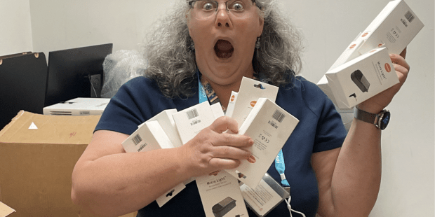 Texas Technology Access Program staff member holding several boxes of switches with a funny shocked and surprised look on her face