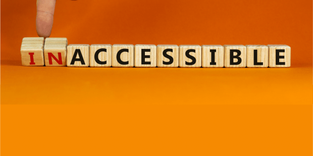 An image of a wooden blocks in a single line to spell INACCESSIBLE. A hand coming down from the top of the image using their