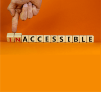 An image of a wooden blocks in a single line to spell INACCESSIBLE. A hand coming down from the top of the image using their