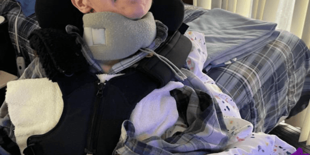 A photo of Jonathan, he has short dark brown hair and brown eyes, he is wearing a grey plaid shirt and he is smiling.