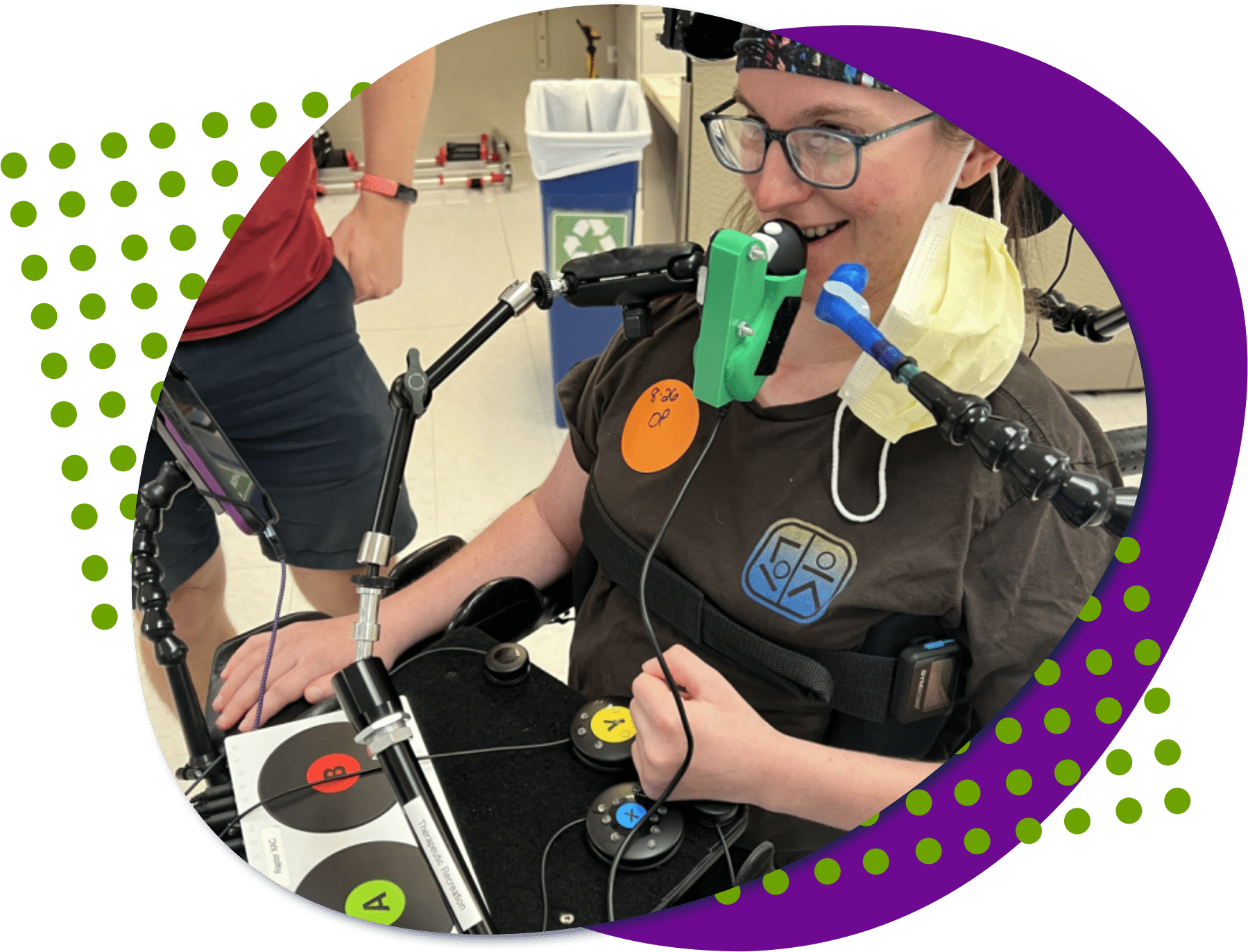 july blog stack image an image of a young woman, she is smiling and using several adaptive gaming devices to play a video game