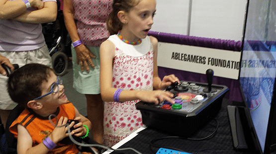 Two kids with disabilities play video games at an AbleGamers Booth