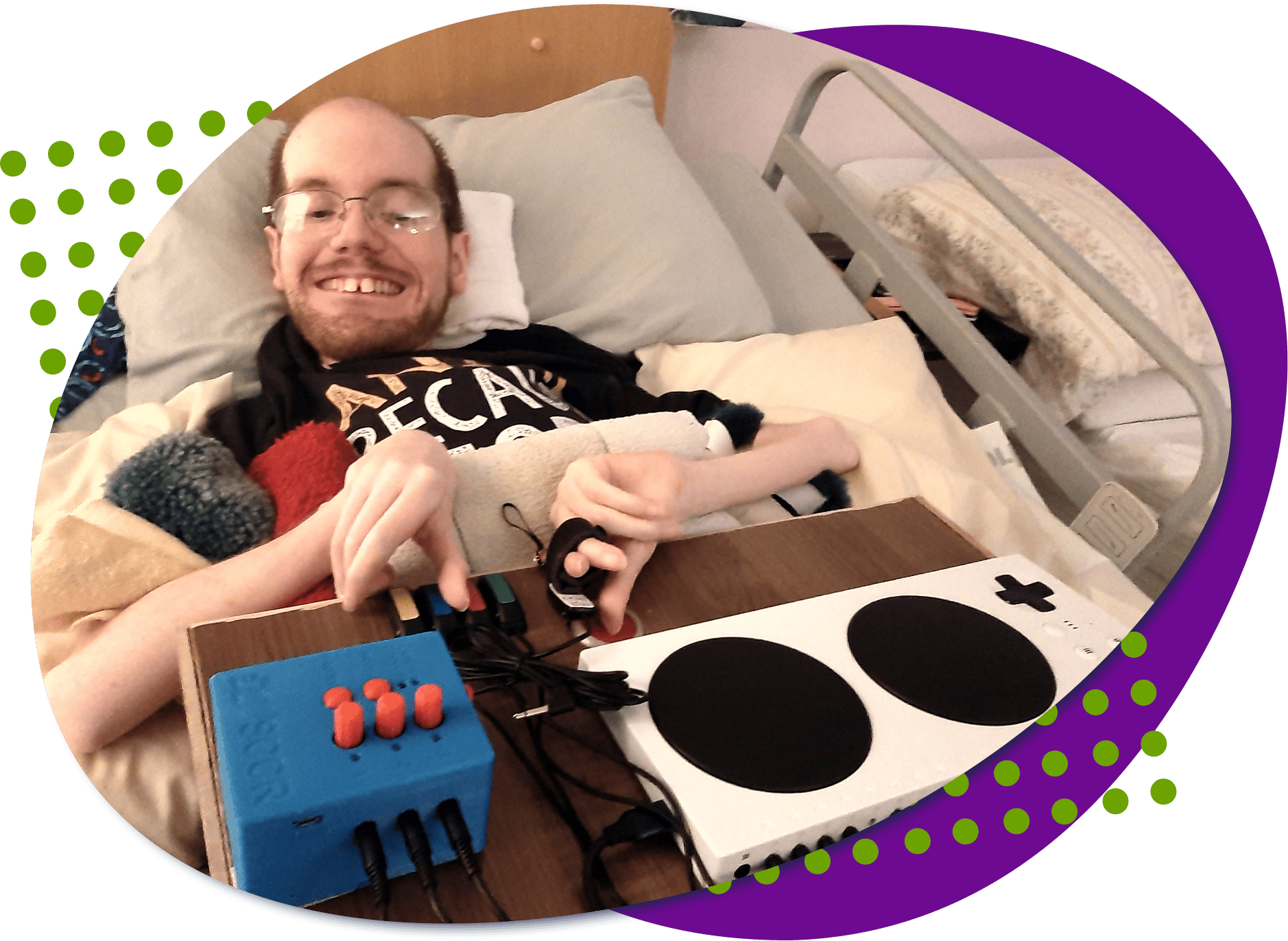 Kody is laying in bed, in front of him is a custom controller, including an XAC