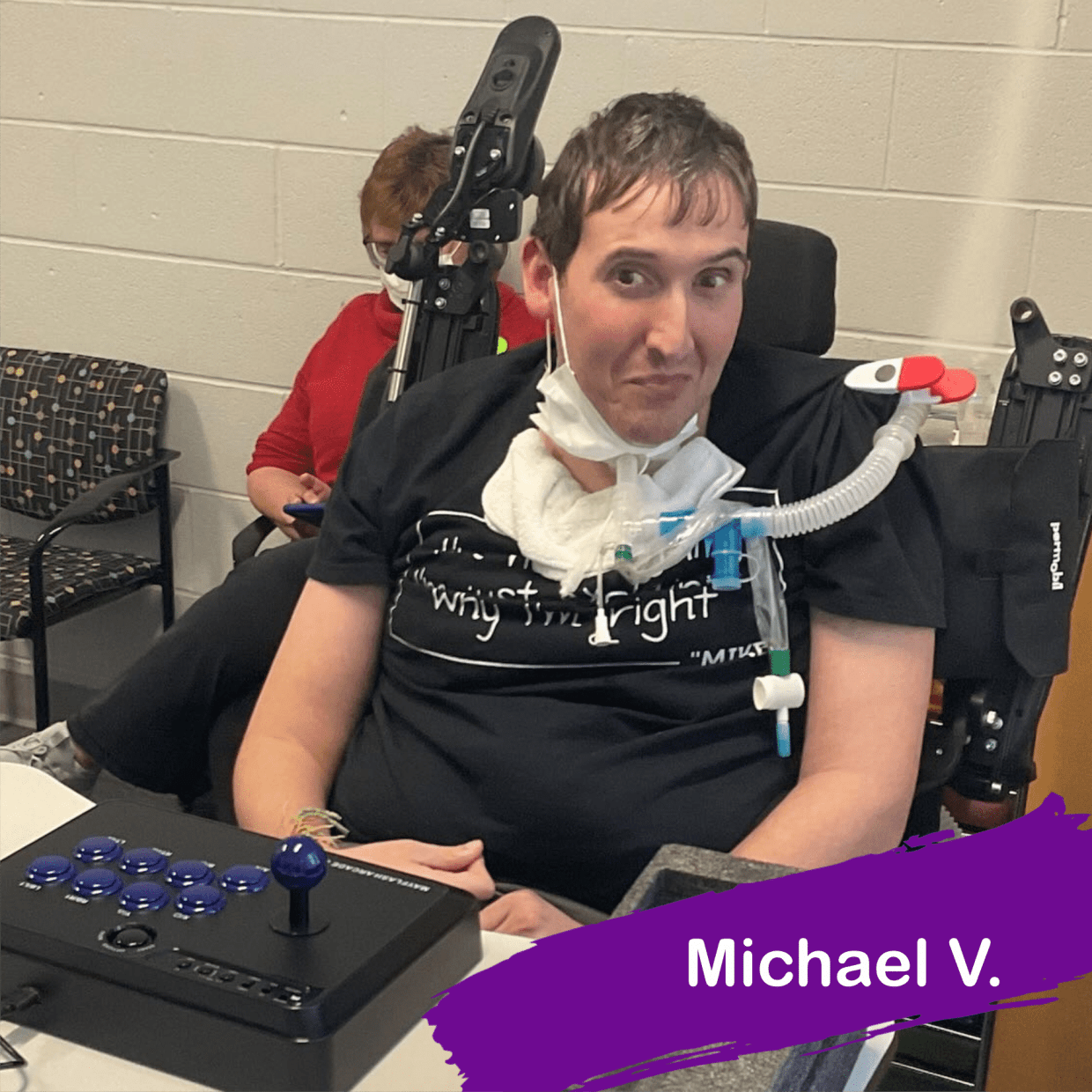 Michael in his wheelchair, in front of him is an arcade stick and an XBox controller