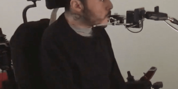 Walter is wearing black and is in a wheelchair, he is blowing into a quadstick.