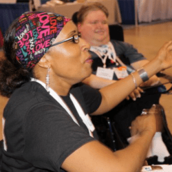 a woman having a lot of fun playing video games Steve Spohn is in the background watching